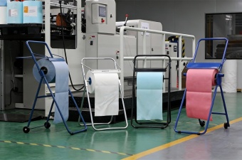 Industrial Roll Dispenser Stand with baked enamel finish and lockable wheels in industrial setting